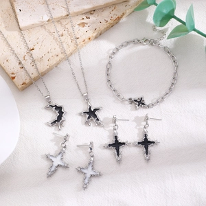 Close-up of silver celestial jewelry set with moon and star charms on white linen