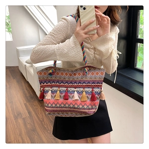 Close-up of bohemian woven tote bag featuring geometric patterns and colorful tassels