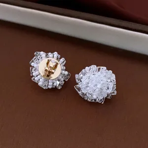 Elegant floral cluster stud earrings with white pearls and crystals on leather background