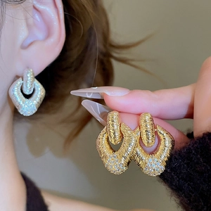 Dettaglio di orecchini vintage in oro con pendente a rombo e diamanti indossati