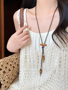 Détail du collier bohème en cordon de cire avec perles de bois et pendentif à franges