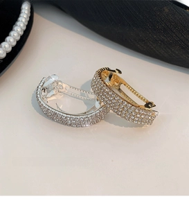 Detailed view of curved gold and silver ponytail clips with dense rhinestone inlay