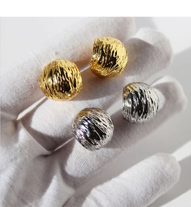Macro detail of gold and silver C-shaped earrings with textured molten lava surface