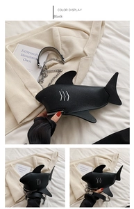 Detail of shark-shaped black pebbled leather crossbody bag with silver zipper and chain
