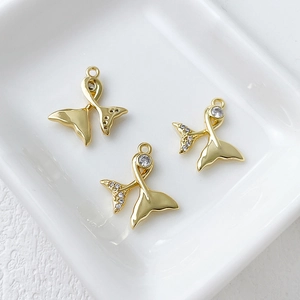 Detailed view of 14k gold-plated mermaid tail charms with sparkling zircons in a tray