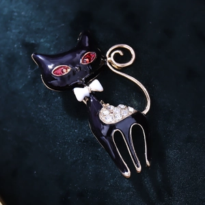Close-up of black enamel cat brooch with red rhinestone eyes and crystal accents