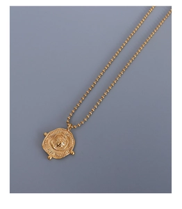 Macro view of gold pendant necklace with sunburst texture and fine beaded chain