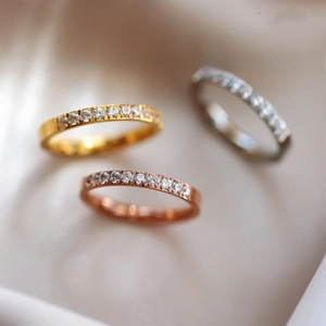 Close-up of minimalist titanium steel rings with half-circle CNC diamond inlay in three colors