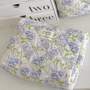 Close-up of quilted floral cosmetic bag with blue flower patterns and fabric label
