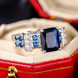 Macro shot of rectangular blue zircon ring nestled in a luxury red hexagonal gift box