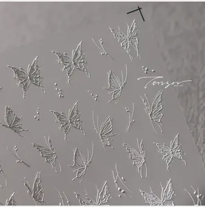 Macro shot of 3D embossed white butterfly nail art stickers with intricate texture