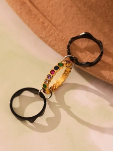 Détail de la bague multicouche dorée avec zircons colorés et anneaux noirs ondulés