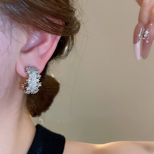 Side view detail of a C-shaped wide silver earring with shimmering cubic zirconia inlay