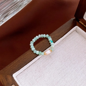 Detailed macro view of handmade amazonite bead ring with baroque pearl on wooden box