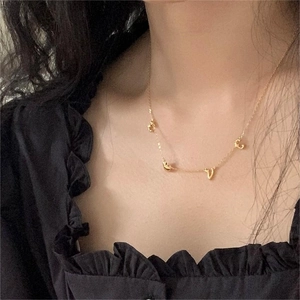 Close-up of minimalist gold-plated LOVE letter charms on a dainty clavicle necklace