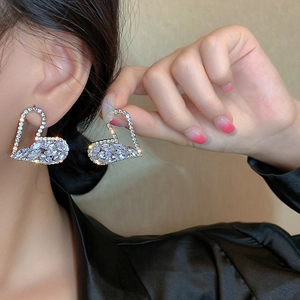 Macro detail of heart-shaped silver earrings with sparkling zircon and marquise-cut stones