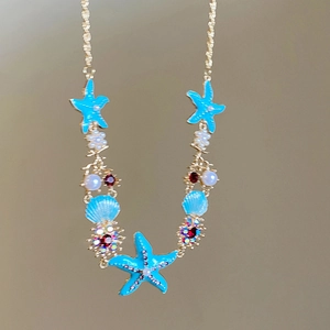 Detail of seaside necklace with blue enamel starfish, seashells and pearls