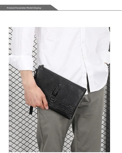 Detail of men's black crocodile pattern clutch bag held by model with wrist strap