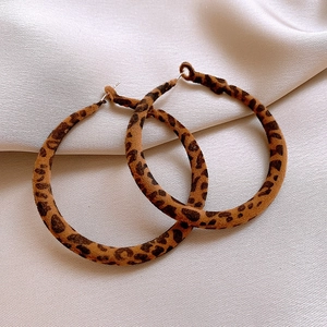 Macro detail of leopard print flocking texture on large hoop earrings with metal studs