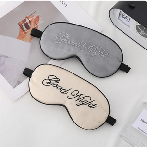 Detailed view of silk-like sleep masks in grey and beige with Good Night embroidery