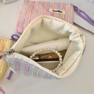 Innenansicht der Tweed-Kosmetiktasche zeigt Stauraum mit Handcreme und Schmuckstücken