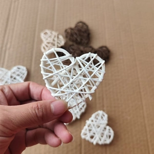 Detail showing a white heart-shaped wicker decoration held by hand with natural fiber texture