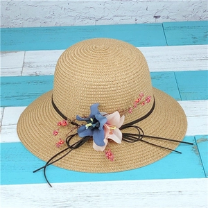 Dettaglio cappello in paglia intrecciata con giglio blu navy e decorazione di bacche rosa