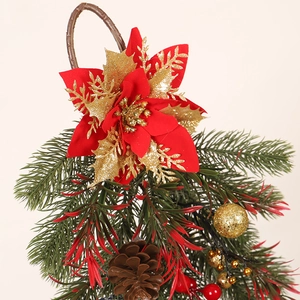 Christmas teardrop swag with red poinsettia, pine cones, and gold ornaments on beige wall