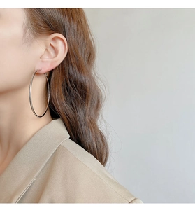 Side view of model wearing large silver hoop earrings in minimalist style