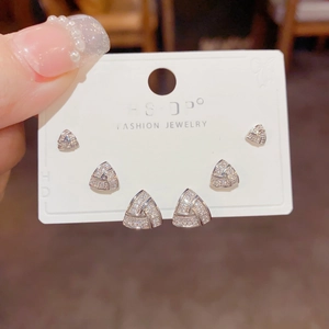 Detailed view of three pairs of silver geometric triangle stud earrings with zircons