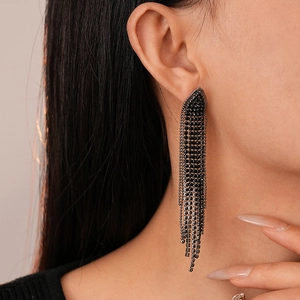 Detail of long black tassel earrings with a diamond-set triangle top on a model