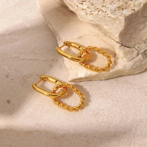Detail shot of golden twisted rope earrings on a natural stone textured background