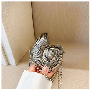 Macro view of silver nautilus shell evening bag featuring detailed spiral metal texture