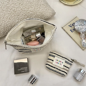 Close-up of striped canvas makeup bag set featuring blue stripes and fringed edge details