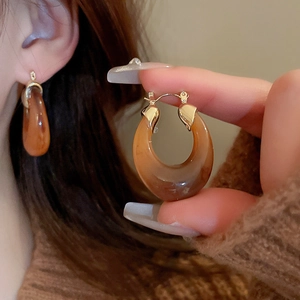 Detail shot of amber resin U-shaped earrings with vintage gold metal accents