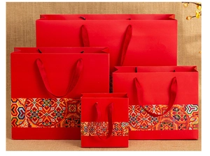 Detail of four Chinese style red paper gift bags with traditional patterns and rope handles