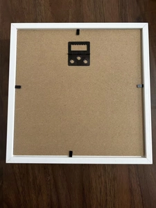 Detail of the MDF backboard with black sawtooth hanger and metal clips on white frame