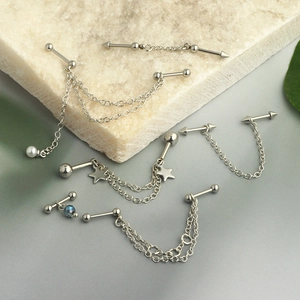 Detail of silver star pearl ear chain with stainless steel studs on marble background