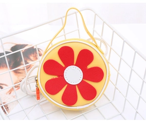 Dettaglio della borsa a tracolla rotonda gialla con girasole in un cesto bianco