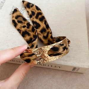 Detailed view of hammered gold cuff bracelet with leopard print fabric wrap on book