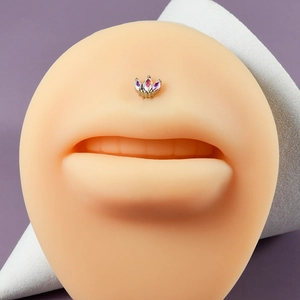 Silver stainless steel lip stud with crown-shaped opal gems on a silicone model lip