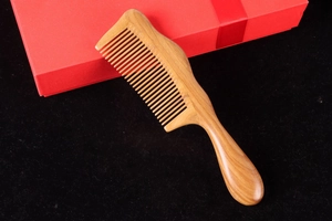 Macro detail of high-quality green sandalwood comb with fine teeth and a red gift box