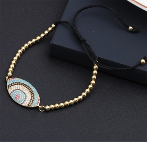 Detail of adjustable evil eye bracelet with colorful zircons and golden beaded cord