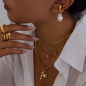 Gros plan de colliers dorés à plusieurs rangs avec pendentif cadenas et boucles d'oreilles