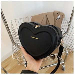 Dettaglio della borsa a tracolla nera a forma di cuore con scritte dorate alla moda