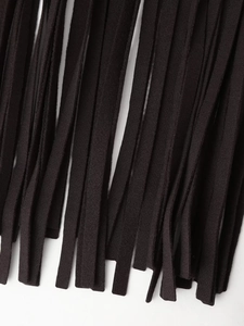 Close-up detail of black woven tassels and textured fabric on women's wool coat