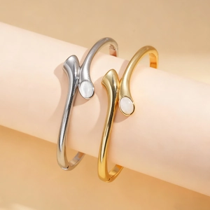 Bracciali placcati in oro 18K e argento con pietre preziose ovali bianche su sfondo moderno