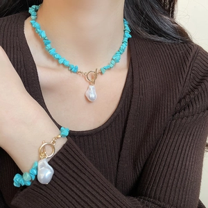 Close-up of bohemian turquoise stone set with baroque pearl and golden toggle clasp