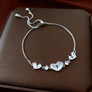 Adjustable silver bracelet with zircon hearts and bow detail on brown jewelry box