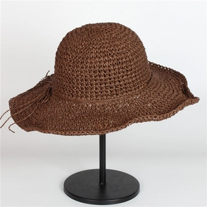 Dettaglio cappello da sole in paglia intrecciata a mano marrone scuro con tesa larga e nappine